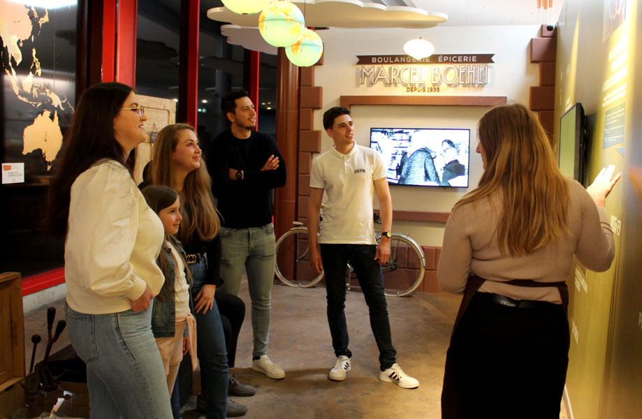 Photo d'un groupe en visite à la Fabrique à Bretzels, ils écoutent les explications en souriant